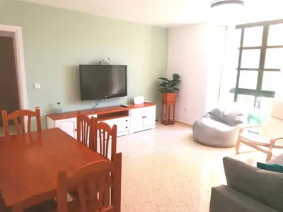a living room with a table and a flat screen tv at Apartamento Tres Carabelas, AC, Wifi, Parking in Sanlúcar de Barrameda