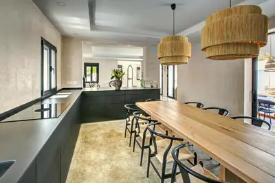 a kitchen with a long wooden table and chairs at Villa Mas Tranquila - A stylish villa with pool 150 m from the beach in Conil de la Frontera