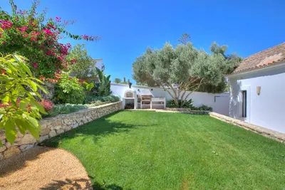 a yard with a stone retaining wall and a grass yard at Villa Mas Tranquila - A stylish villa with pool 150 m from the beach in Conil de la Frontera