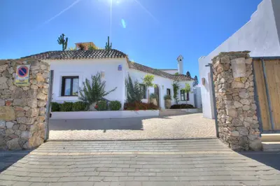 a white house with a gate and a stone wall at Villa Mas Tranquila - A stylish villa with pool 150 m from the beach in Conil de la Frontera
