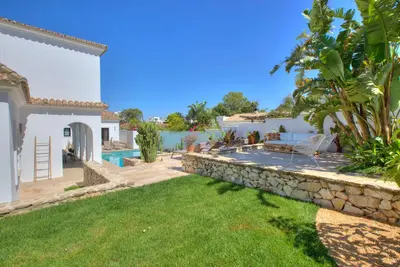 a backyard with a stone retaining wall and a swimming pool at Villa Mas Tranquila - A stylish villa with pool 150 m from the beach in Conil de la Frontera