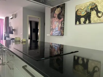 a kitchen with a black counter top and paintings on the wall at Piso Centro La Morena, Climatizado, Wifi in Sanlúcar de Barrameda
