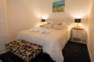 a bedroom with a large white bed with two lamps at El Sabor del Sur, Apartamentos Living Sur in Sanlúcar de Barrameda