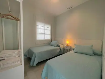 a bedroom with two beds and a window at El Sabor del Sur, Apartamentos Living Sur in Sanlúcar de Barrameda