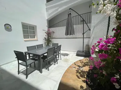 a dining room with a table and chairs and flowers at El Sabor del Sur, Apartamentos Living Sur in Sanlúcar de Barrameda