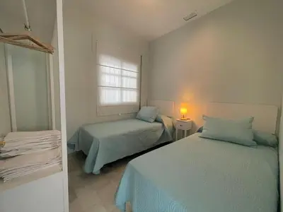 a bedroom with two beds and a window at El Sabor del Sur, Apartamentos Living Sur in Sanlúcar de Barrameda