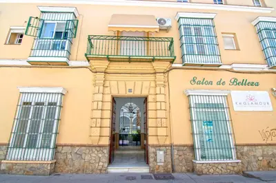 a yellow building with windows and a door at El Sabor del Sur, Apartamentos Living Sur in Sanlúcar de Barrameda