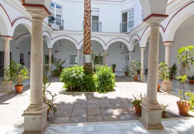 a courtyard with palm trees and plants in a building at El Sabor del Sur, Apartamentos Living Sur in Sanlúcar de Barrameda