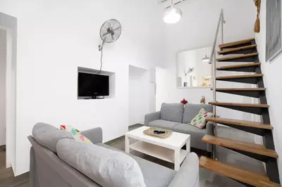 a living room with a gray couch and a staircase at Precioso alojamiento con patio interior in Cádiz