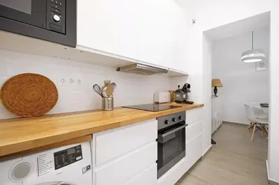 a kitchen with white cabinets and a wooden counter top at Precioso alojamiento con patio interior in Cádiz