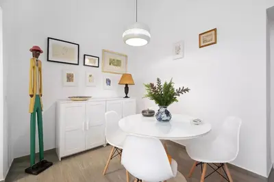 a white dining room with a white table and white chairs at Precioso alojamiento con patio interior in Cádiz