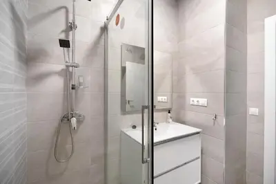 a white bathroom with a shower and a sink at Precioso alojamiento con patio interior in Cádiz