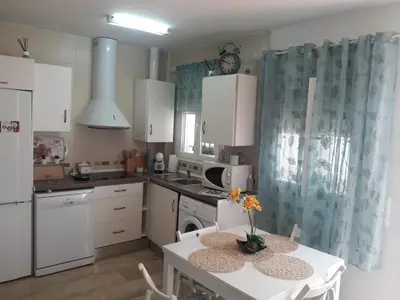 a kitchen with white cabinets and a table with flowers on it at El Ancla in Chiclana de la Frontera
