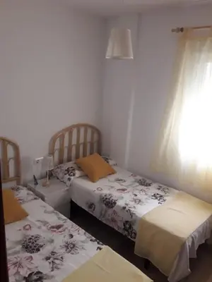 two twin beds in a room with a window at El Ancla in Chiclana de la Frontera