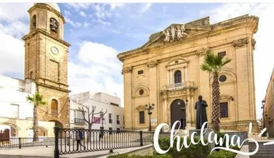 a large building with a clock tower and a church at El Ancla in Chiclana de la Frontera