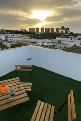 a table and benches on a rooftop with a view of a city at Atico duplex con Terraza en pleno centro de Jerez in Jerez de la Frontera