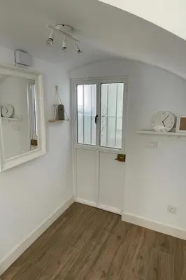 a white room with a door and a clock on the wall at Atico duplex con Terraza en pleno centro de Jerez in Jerez de la Frontera
