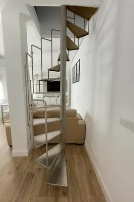 a spiral staircase in a room with a couch at Atico duplex con Terraza en pleno centro de Jerez in Jerez de la Frontera