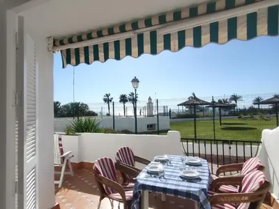 a table and chairs on a patio with a view of the ocean at Pinar de Don Jesus Aries in Novo Sancti Petri