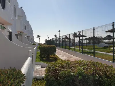 a fence next to a walkway next to a building at Pinar de Don Jesus Aries in Novo Sancti Petri