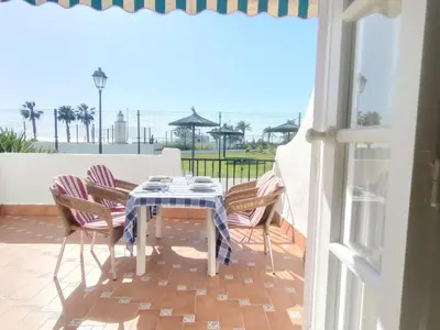 a table and chairs on a balcony with a view of the ocean at Pinar de Don Jesus Aries in Novo Sancti Petri