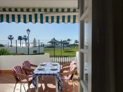 a table and chairs on a patio with a view of the ocean at Pinar de Don Jesus Aries in Novo Sancti Petri