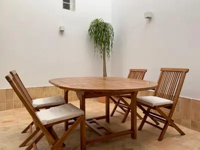a wooden table with four chairs and a potted plant at Plateros 48 Apartamento in Sanlúcar de Barrameda