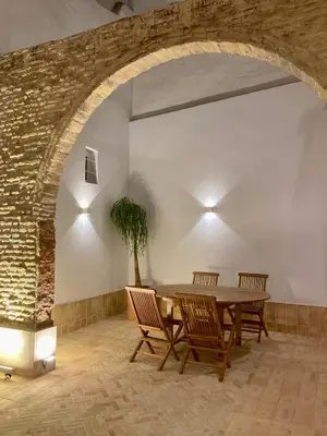 a dining room with a table and chairs and a brick wall at Plateros 48 Apartamento in Sanlúcar de Barrameda