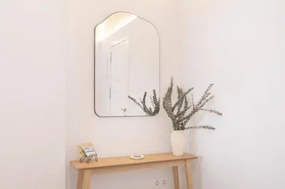 a mirror on a wall above a table with a plant at Plateros 48 Apartamento in Sanlúcar de Barrameda