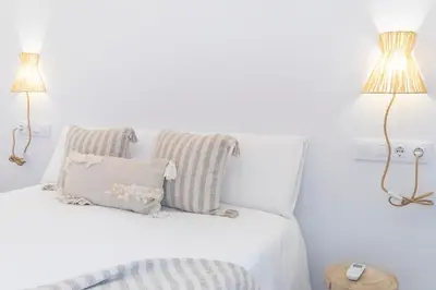 a white bedroom with two lamps and a bed at Plateros 48 Apartamento in Sanlúcar de Barrameda