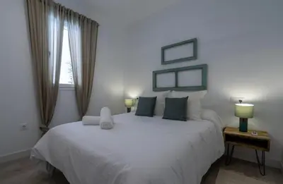a bedroom with a large white bed and a window at El Mirador de El Puerto in El Puerto de Santa María