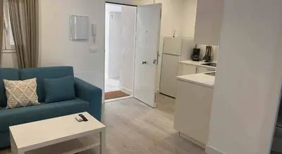 a living room with a blue couch and a kitchen at El Mirador de El Puerto in El Puerto de Santa María