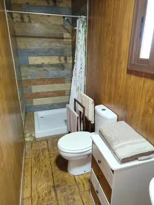 a bathroom with a toilet and a wooden wall at Bungalow para quienes buscan tranquilidad in Chiclana de la Frontera