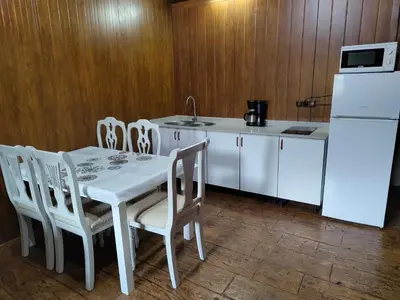 a kitchen with a white table and chairs and a refrigerator at Bungalow para quienes buscan tranquilidad in Chiclana de la Frontera