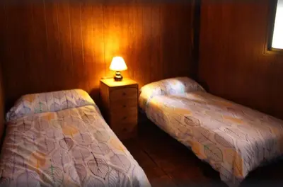 two beds in a room with a lamp on a table at Bungalow para quienes buscan tranquilidad in Chiclana de la Frontera