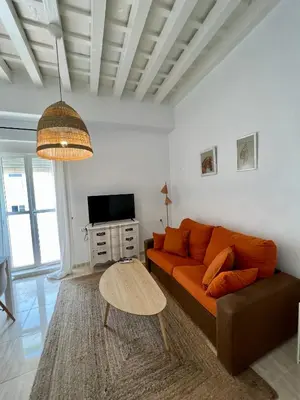 a living room with an orange couch and a table at La Roca del Sur by Cadiz Time in Cádiz