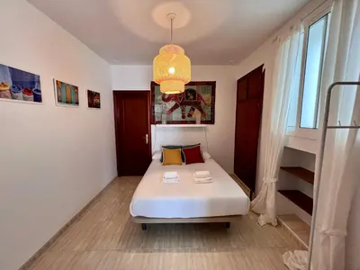 a small bedroom with a bed and a chandelier at La Roca del Sur by Cadiz Time in Cádiz