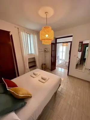 a bedroom with a large white bed and a chandelier at La Roca del Sur by Cadiz Time in Cádiz
