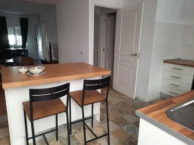 a kitchen with two bar stools and a counter at Casa Amapola - Costa Bahía de Cádiz in Puerto Real