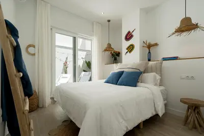 a bedroom with a large white bed with blue pillows at Mistral playa la caleta Ascensor Grupo AC Gestion in Cádiz