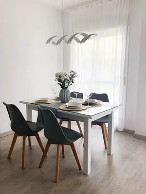 a dining room table with chairs and a vase with flowers at Playa Laguna Bajo Parking in Chipiona