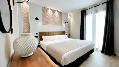 a bedroom with a white bed and a brick wall at Aparthotel Luz de Gades - Suites Spa Gym - Adults Only in Cádiz