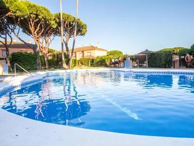 a large blue swimming pool with trees and a house at GuestReady - Chiclana Labarrosa in Novo Sancti Petri