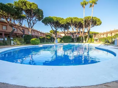 a large swimming pool with palm trees and buildings at GuestReady - Chiclana Labarrosa in Novo Sancti Petri