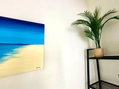 a plant on a shelf next to a painting of a beach at La Casita del Mar in El Puerto de Santa María