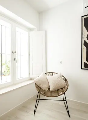 a rattan chair in a white room with windows at Apartamento Mucha Vida Little Apartments in Cádiz