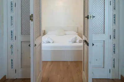 a bedroom with a white bed and two doors at Apartamento Sherezade y la ciudad de Cádiz in Cádiz