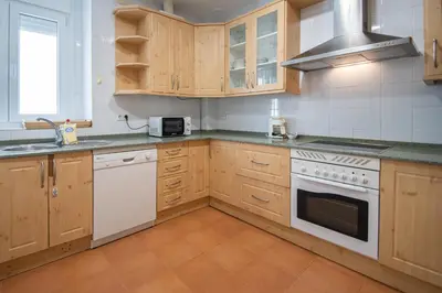 a kitchen with white appliances and wooden cabinets at Apartamento Sherezade y la ciudad de Cádiz in Cádiz