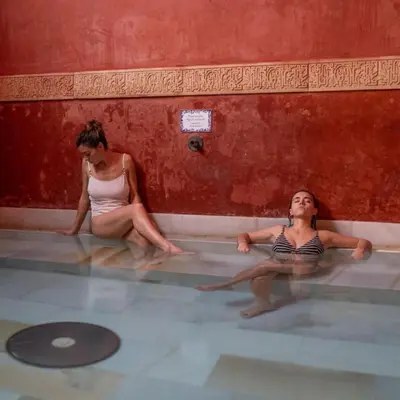 two women are sitting in a swimming pool at Riad Medina Mudéjar Cádiz in Chiclana de la Frontera