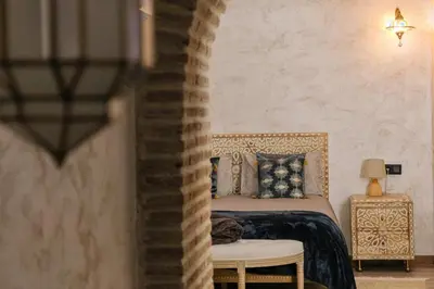 a bedroom with a bed and a chair and a table at Riad Medina Mudéjar Cádiz in Chiclana de la Frontera
